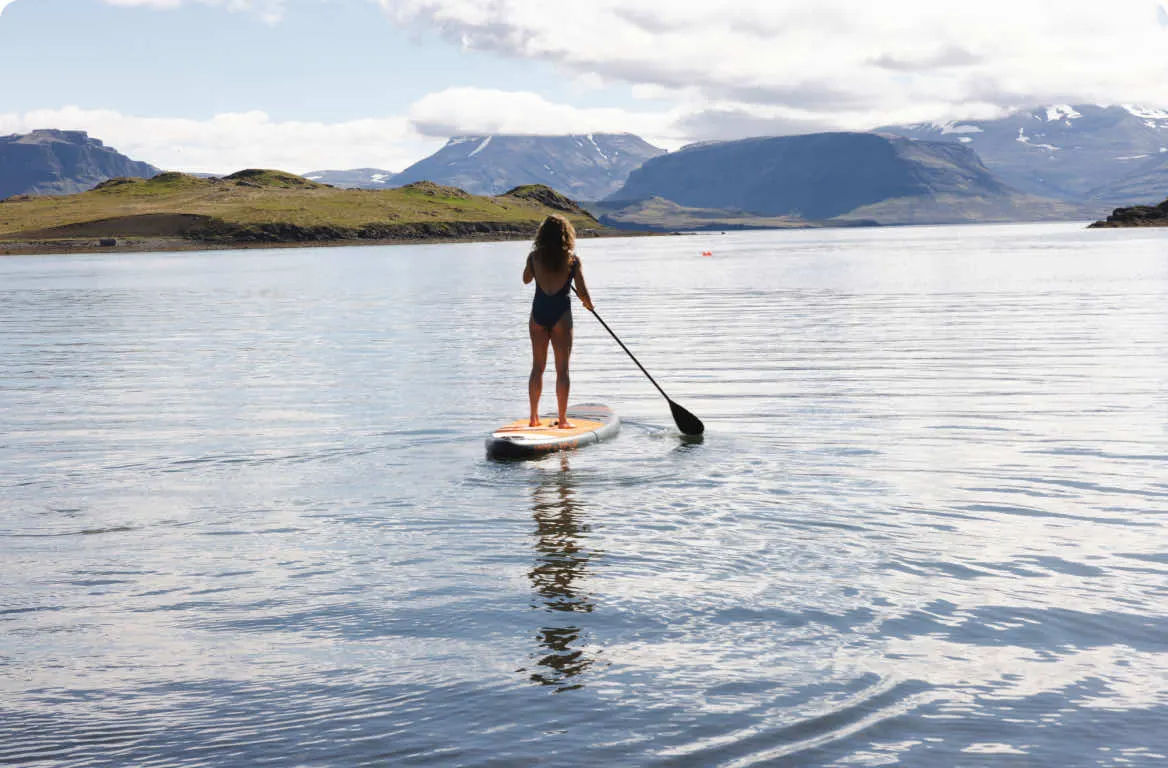 Kona á strandbretti á lygnum firðinum