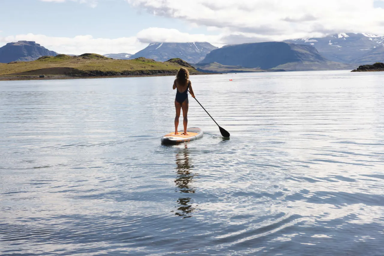 Kona á strandbretti á firðinum