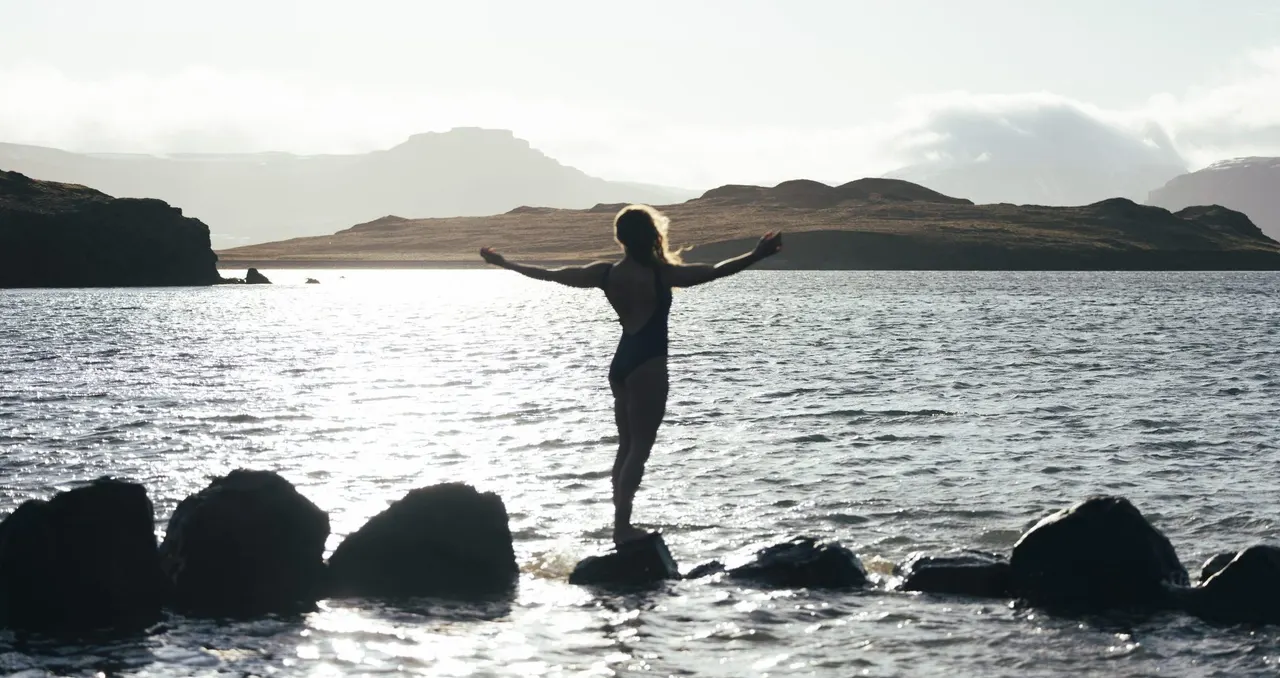 A women standing on rocks with her arms open towards the beautiful Atlantic Ocean