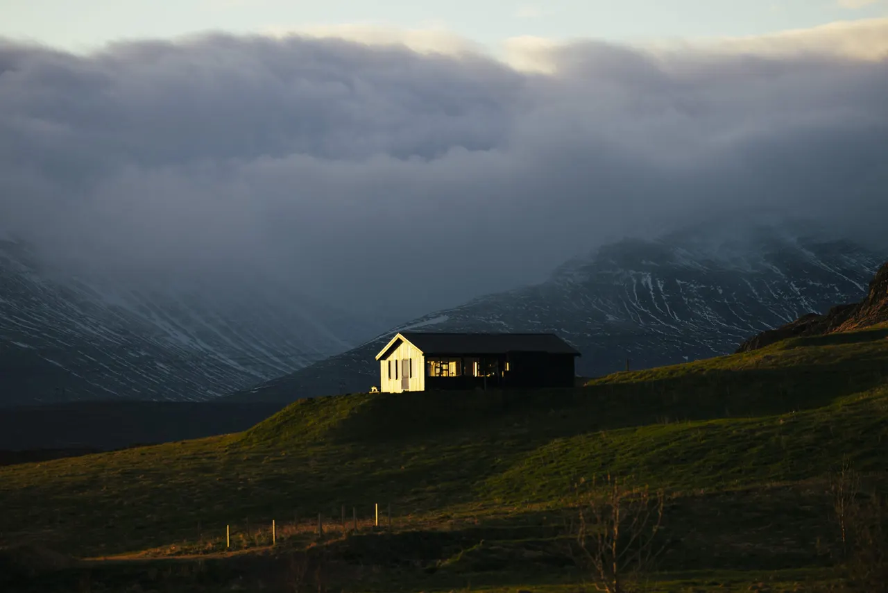 Hús í Hvammsvík undir skýjuðum fjöllum