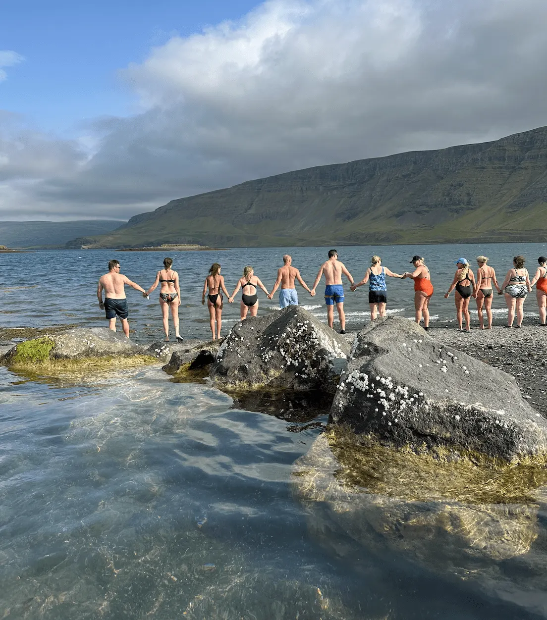 Hópur leiðist í flæðarmálinu fyrir sjósund